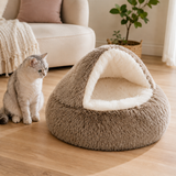 Brown cave pet bed with fluffy white plush interior beside a cat