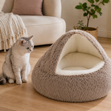 Brown cave pet bed with smooth cream interior beside a cat