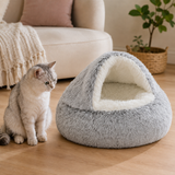Gray cave pet bed with fluffy white plush interior beside a cat