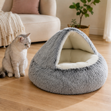 Gray cave pet bed with smooth cream interior beside a cat