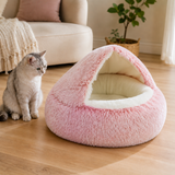 Pink cave pet bed with smooth cream interior beside a cat