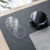 Five clear circular tempered-glass smartwatch screen protectors beside a round watch