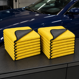 Twenty-pack of 30 by 30 cm yellow and charcoal microfiber car towels on a detailing bench