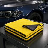 Three 30 by 30 cm yellow and charcoal microfiber car towels on a detailing bench