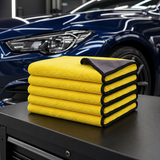Five 30 by 30 cm yellow and charcoal microfiber car towels on a detailing bench