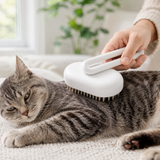 White Handle pet grooming brush used bristle-side down on a gray tabby cat