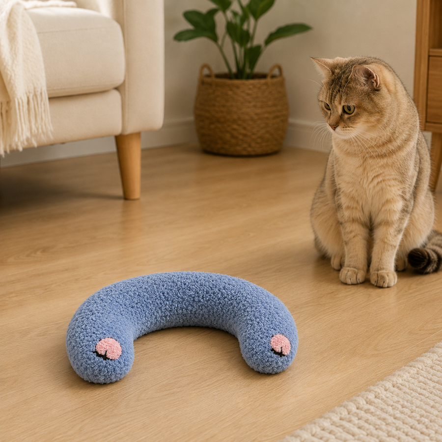 Blue U-shaped plush pet pillow fully visible beside a curious cat in a warm living room