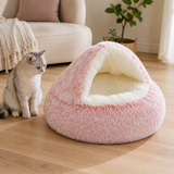 Pink plush cave-style round pet bed fully visible beside a cat