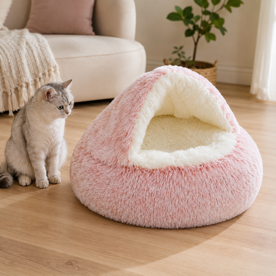 Pink plush cave-style round pet bed fully visible beside a cat